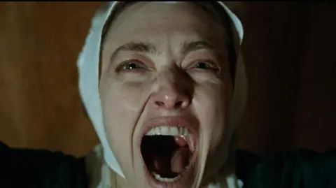 Searchlight Pictures Amanda Seyfried taking part in a religious dance with her arms flung wide and her mouth open